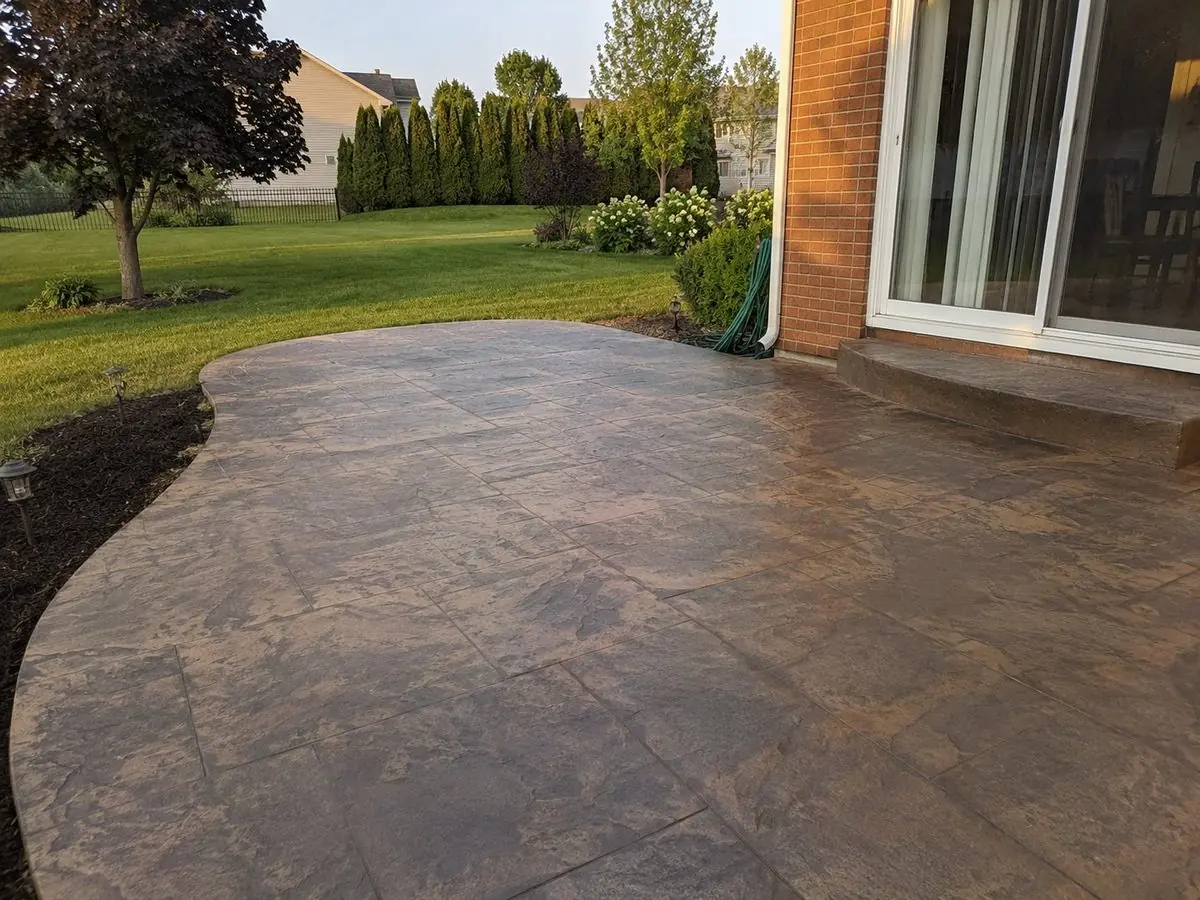 Curved earth-tone stamped concrete patio in Westland, MI